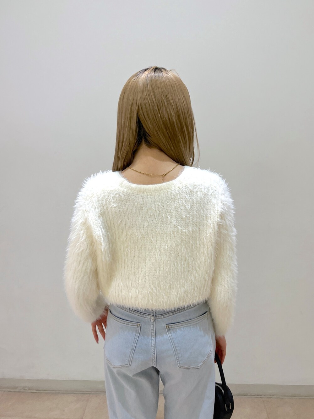 ホワイト系のカーディガン/ボレロ、ブルー系のデニムパンツ、ブラック系のショルダーバッグを着用したレディースの春コーディネートの6枚目の写真