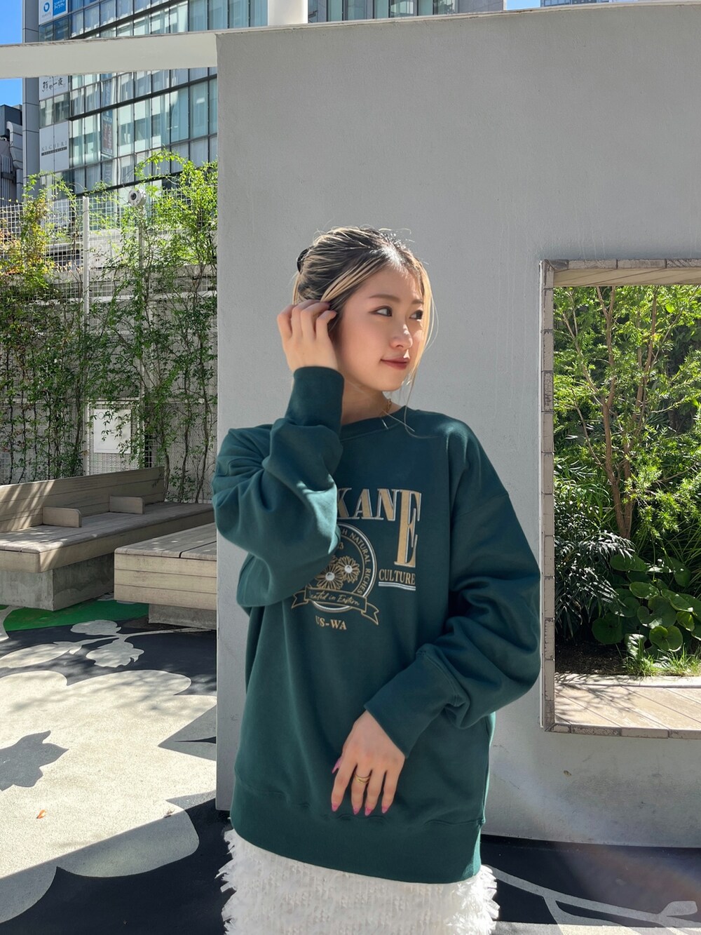 グリーン系のTシャツ/カットソー、ホワイト系のスカート、ブラック系のブーツを着用したレディースの秋コーディネートの6枚目の写真