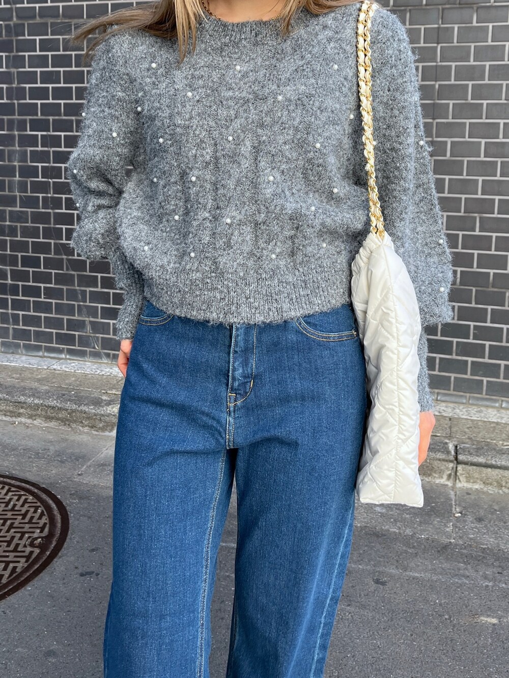 ブルー系のデニムパンツ、グレー系のニット/セーター、ホワイト系のトートバッグを着用したレディースの冬コーディネートの7枚目の写真