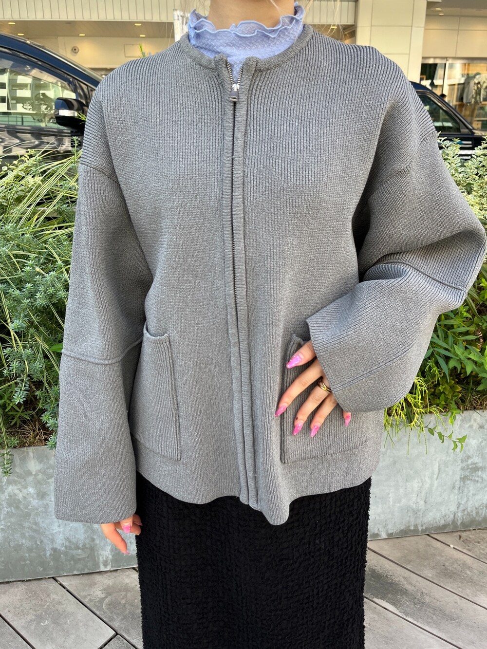 グレー系のカーディガン/ボレロ、ブラック系のスカート、ホワイト系のスニーカーを着用したレディースの秋コーディネートの6枚目の写真