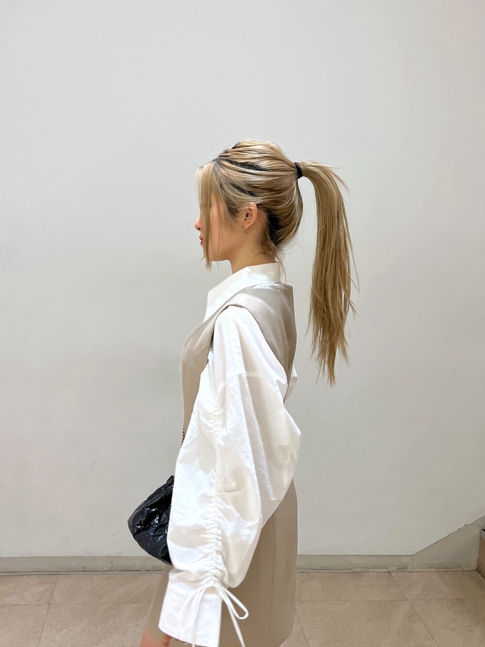 ブラック系のショルダーバッグ、ホワイト系のシャツ/ブラウス、ベージュ系のワンピースを着用したレディースの春コーディネートの6枚目の写真