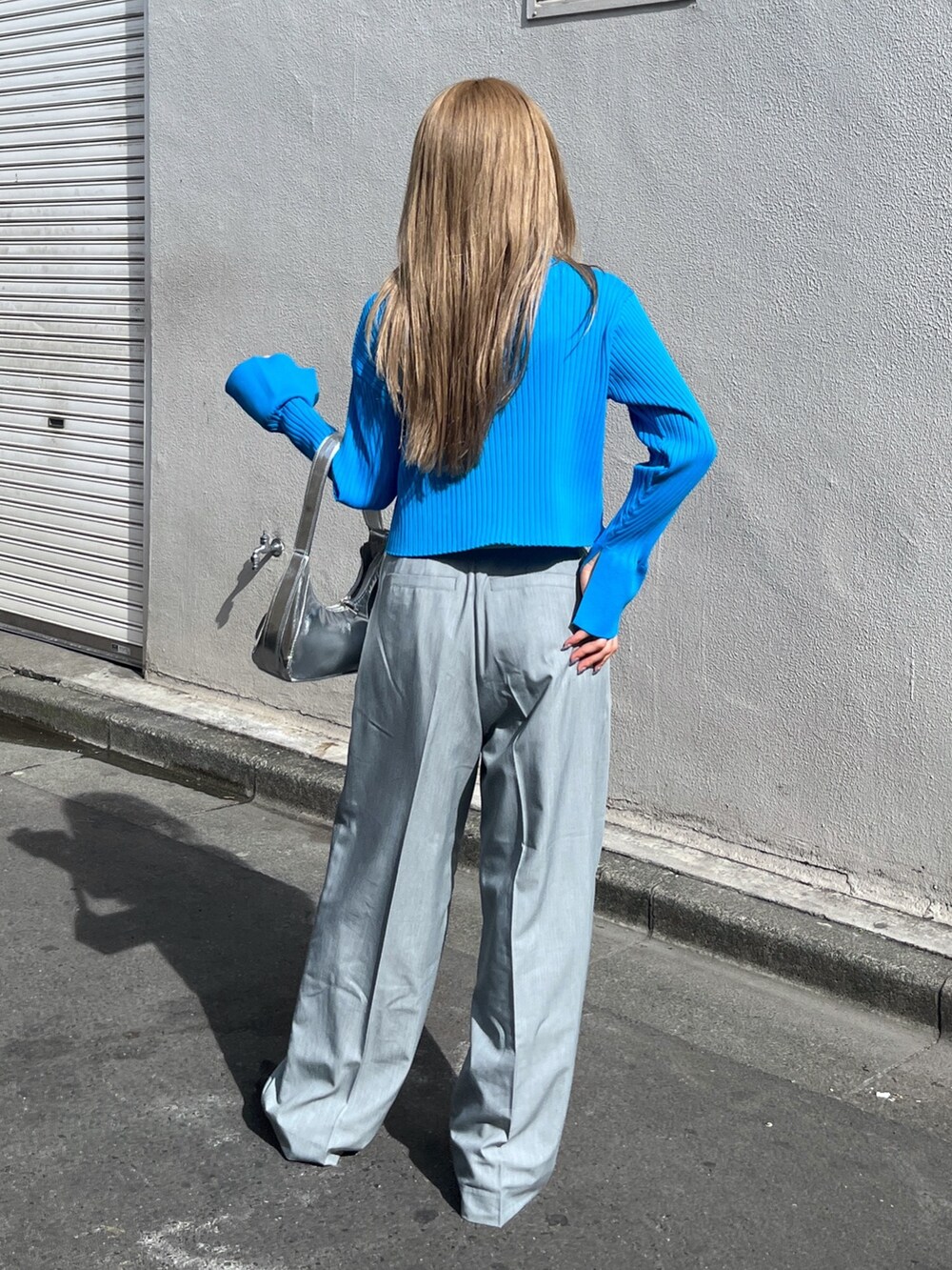 ブルー系のニット/セーター、シルバー系のショルダーバッグ、グレー系のスラックスを着用したレディースの春コーディネートの4枚目の写真