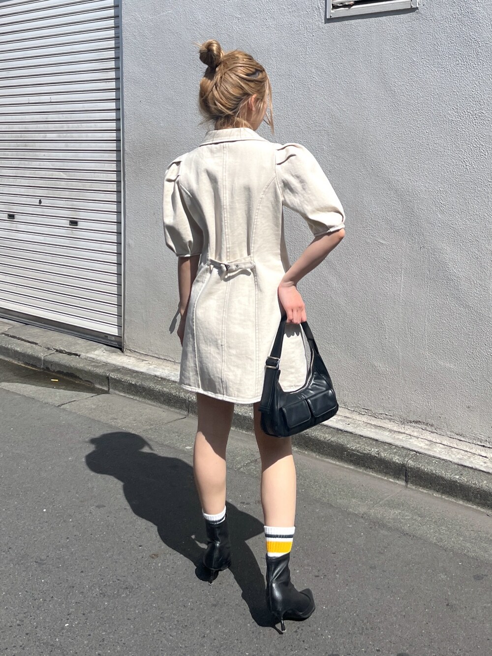 ブラック系のショルダーバッグ、ホワイト系のワンピースを着用したレディースの春コーディネートの3枚目の写真