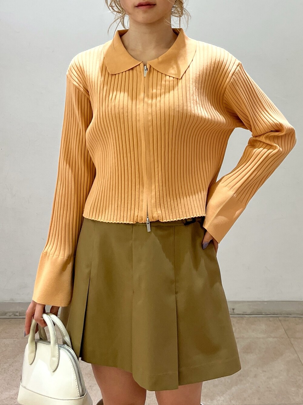 ベージュ系のニット/セーター、ホワイト系のショルダーバッグ、ベージュ系のスカートを着用したレディースの冬コーディネートの9枚目の写真