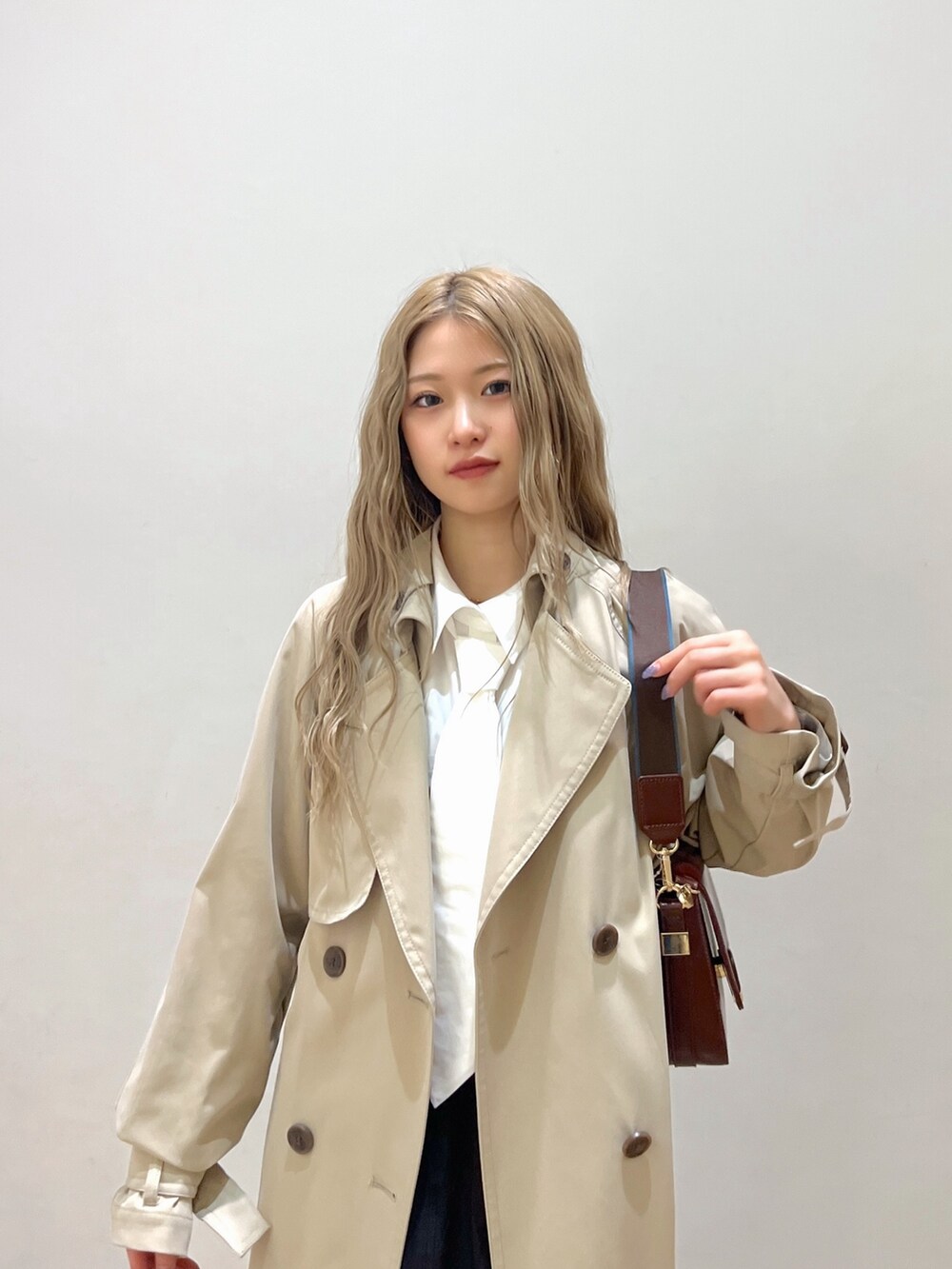 ホワイト系のシャツ/ブラウス、ベージュ系のトレンチコート、ブラウン系のショルダーバッグを着用したレディースの春コーディネートの5枚目の写真