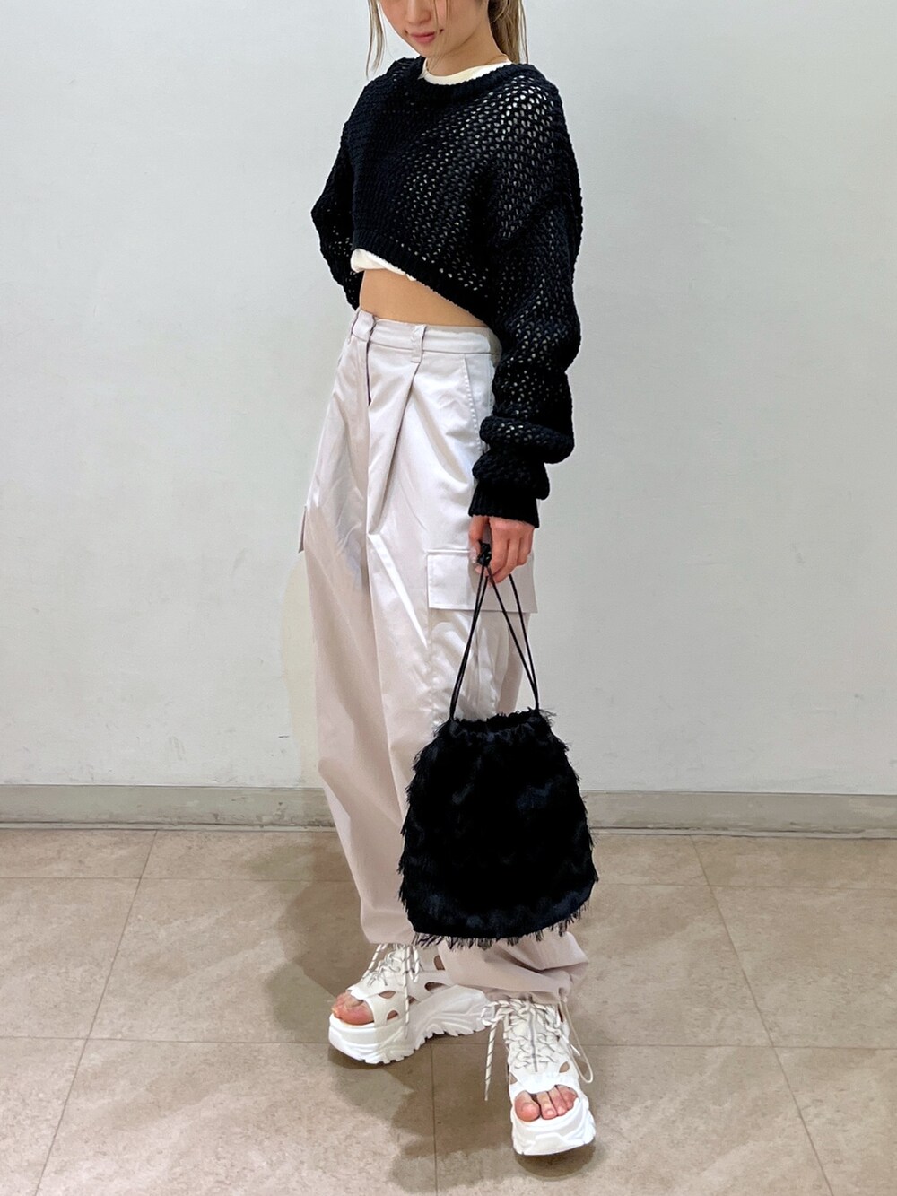 ベージュ系のカーゴパンツ、ブラック系のニット/セーター、ブラック系のハンドバッグを着用したレディースの春コーディネートの4枚目の写真