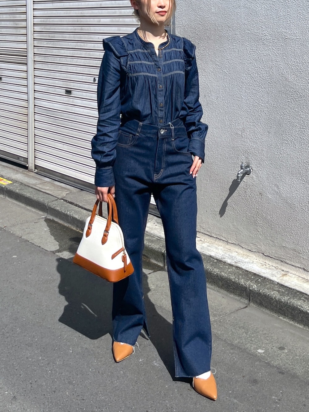 ブルー系のシャツ/ブラウス、ブルー系のデニムパンツ、ブラウン系のショルダーバッグを着用したレディースの春コーディネートの3枚目の写真