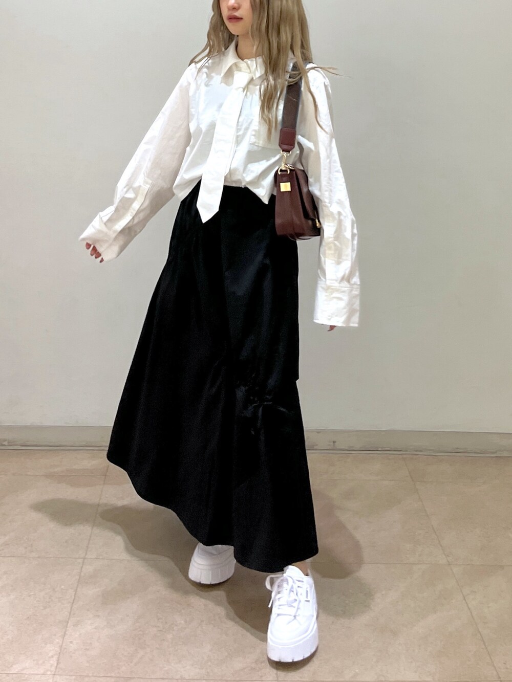 ブラック系のスカート、ホワイト系のシャツ/ブラウス、ブラウン系のショルダーバッグを着用したレディースの春コーディネートの9枚目の写真