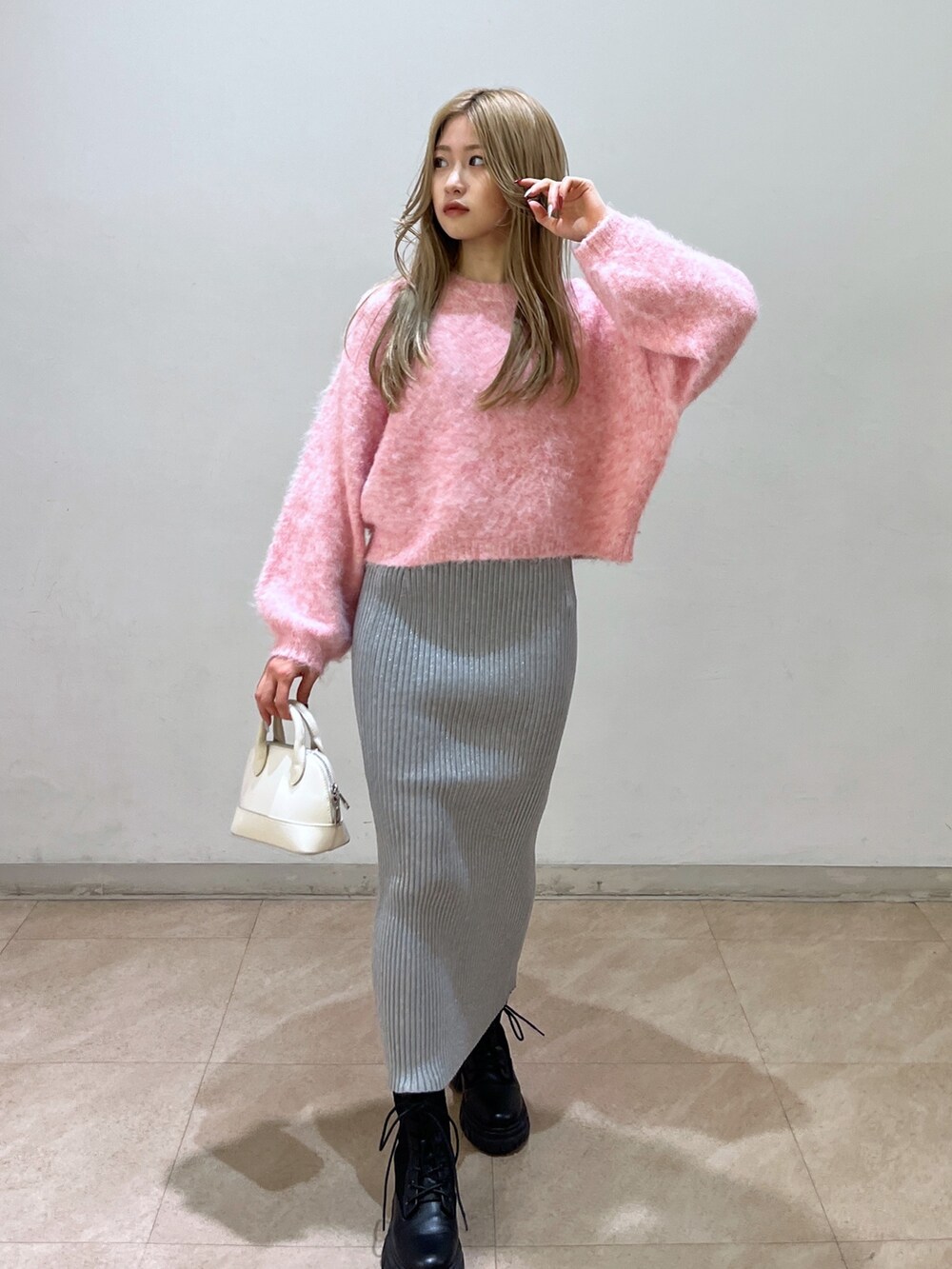 ピンク系のニット/セーター、ブラック系のブーツ、ホワイト系のショルダーバッグを着用したレディースの冬コーディネートの2枚目の写真