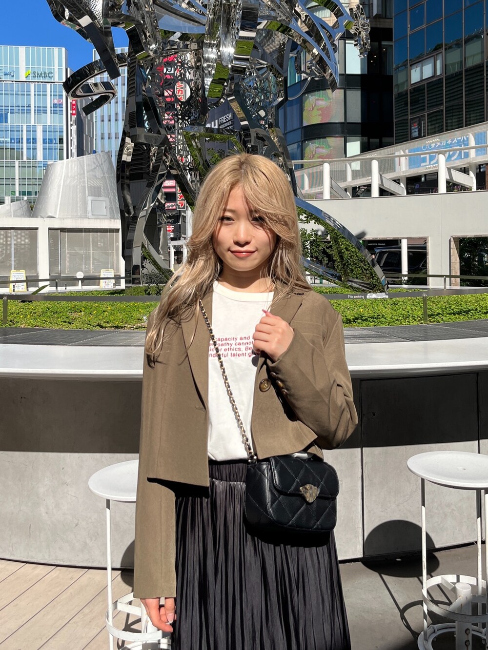 ブラック系のショルダーバッグ、ホワイト系のTシャツ/カットソー、ブラウン系のテーラードジャケットを着用したレディースの秋コーディネートの5枚目の写真