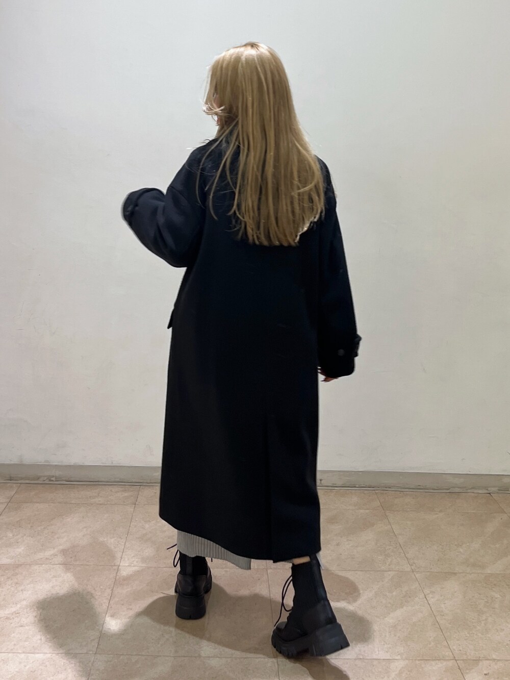 ピンク系のニット/セーター、ブラック系のチェスターコート、ブラック系のブーツを着用したレディースの冬コーディネートの3枚目の写真