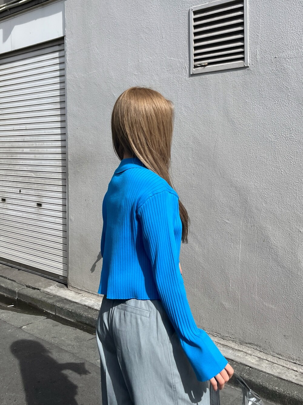 ブルー系のニット/セーター、シルバー系のショルダーバッグ、グレー系のスラックスを着用したレディースの春コーディネートの7枚目の写真