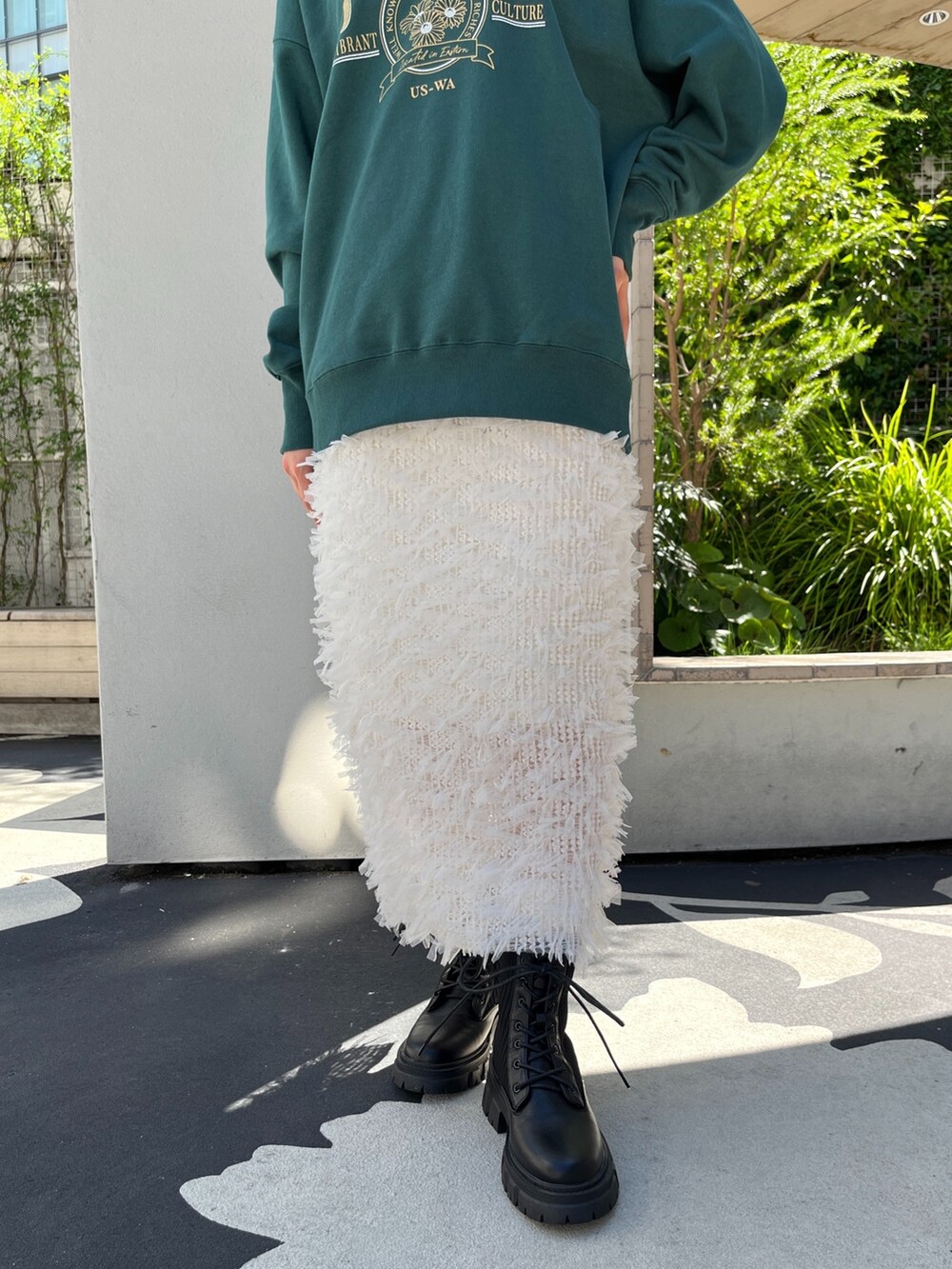 グリーン系のTシャツ/カットソー、ホワイト系のスカート、ブラック系のブーツを着用したレディースの秋コーディネートの8枚目の写真