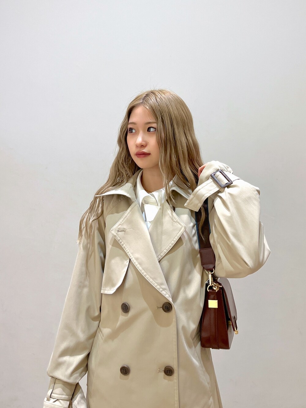 ホワイト系のシャツ/ブラウス、ベージュ系のトレンチコート、ブラウン系のショルダーバッグを着用したレディースの春コーディネートの8枚目の写真