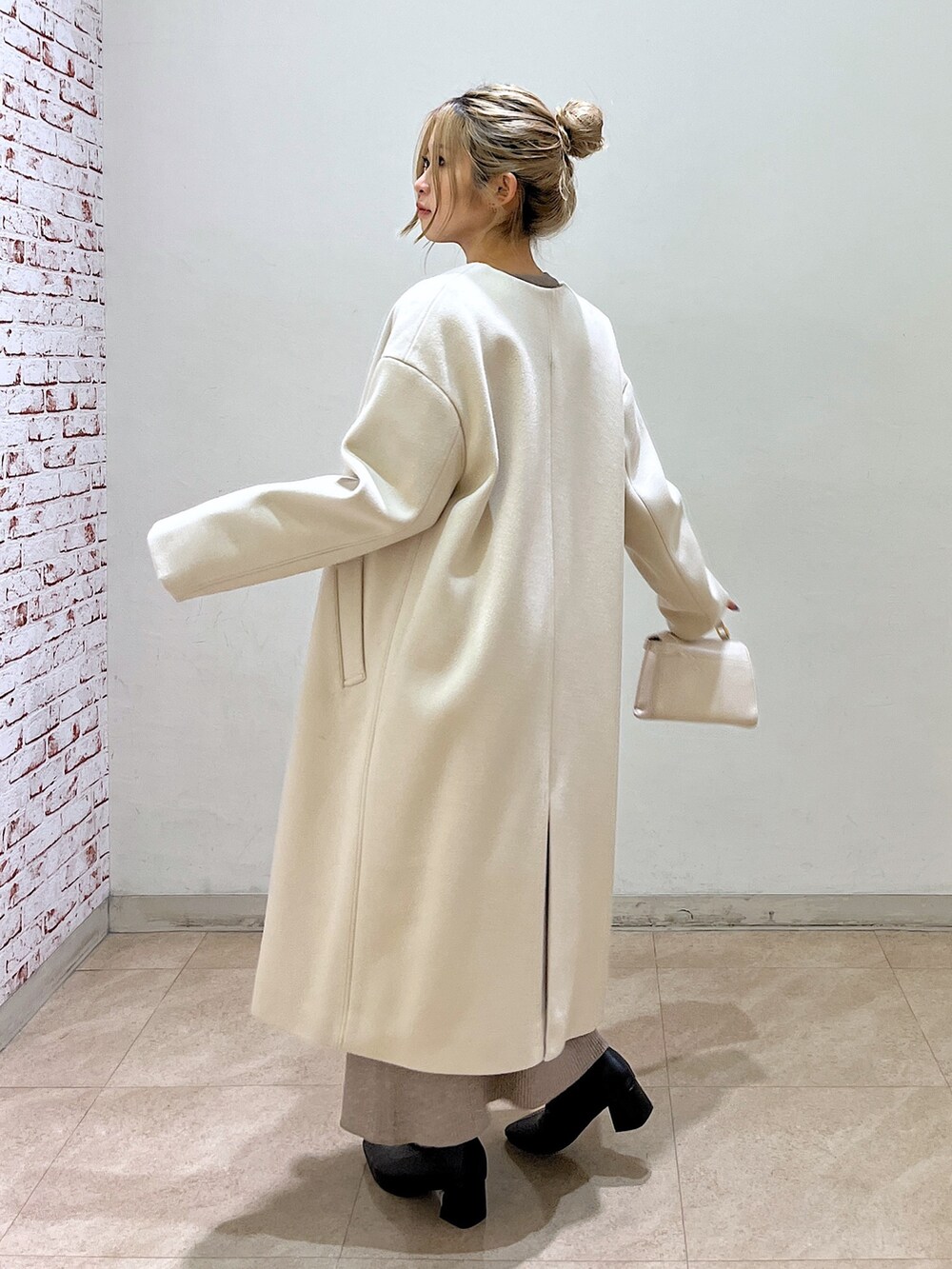 ベージュ系のノーカラーコート、ホワイト系のシャツ/ブラウス、ベージュ系のワンピースを着用したレディースの冬コーディネートの5枚目の写真