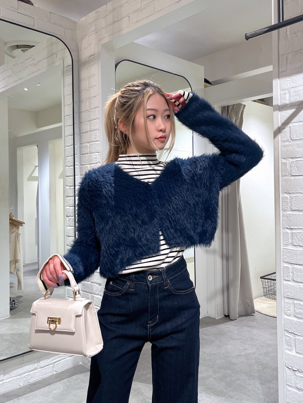 ホワイト系のニット/セーター、ブルー系のカーディガン/ボレロ、ホワイト系のショルダーバッグを着用したレディースの冬コーディネートの7枚目の写真