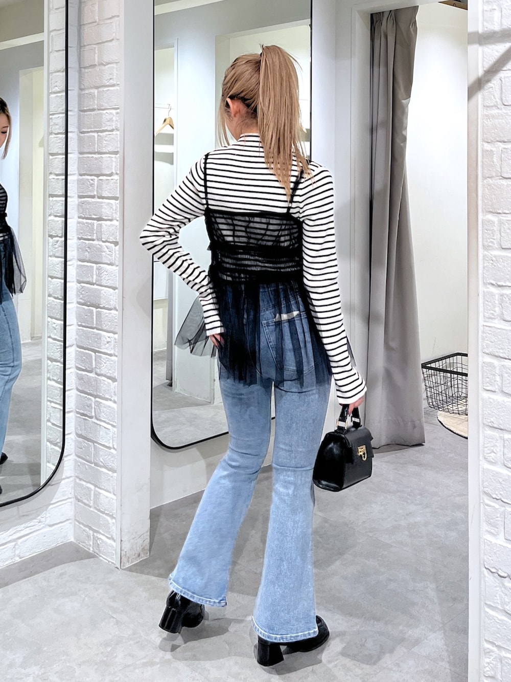 ホワイト系のニット/セーター、ブラック系のシャツ/ブラウス、ブルー系のデニムパンツを着用したレディースの冬コーディネートの4枚目の写真