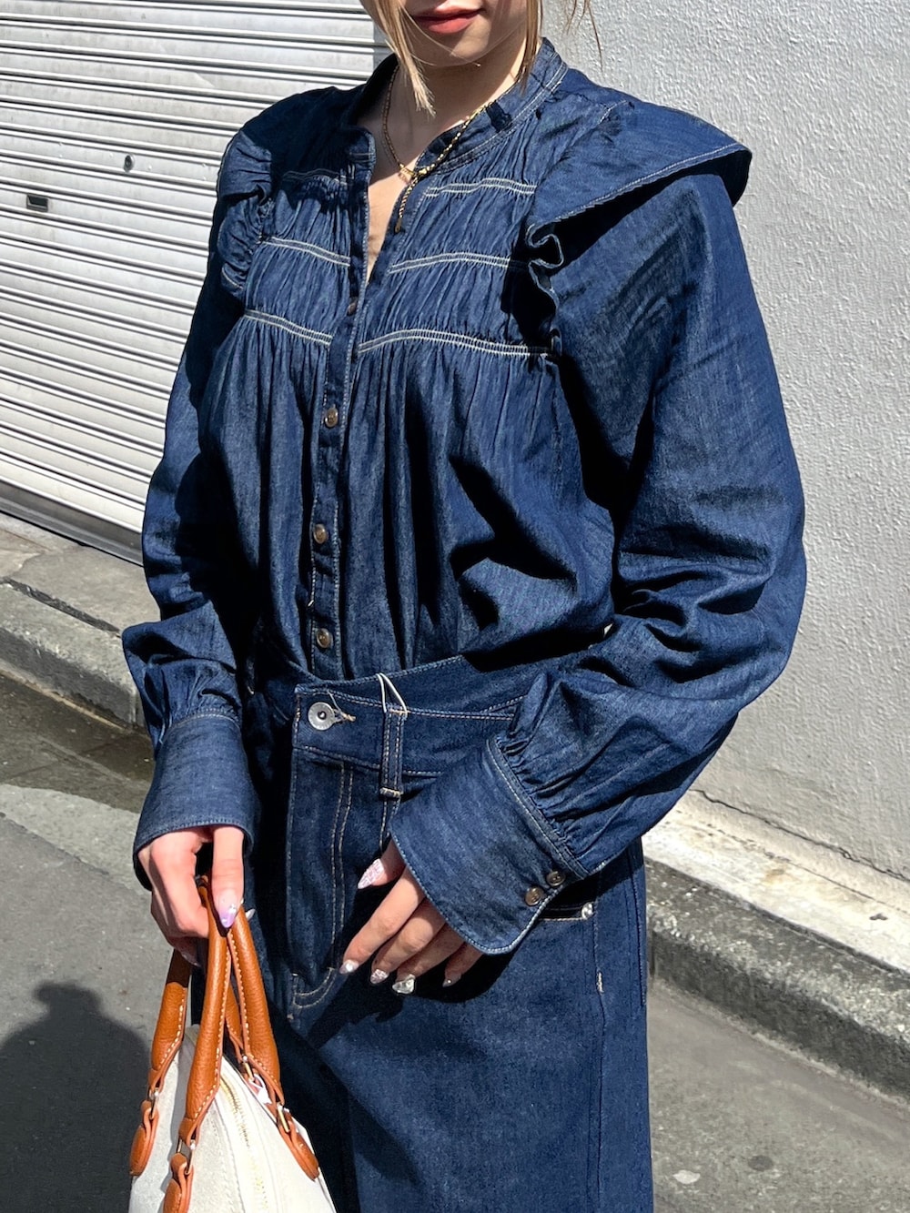 ブルー系のシャツ/ブラウス、ブルー系のデニムパンツ、ブラウン系のショルダーバッグを着用したレディースの春コーディネートの7枚目の写真