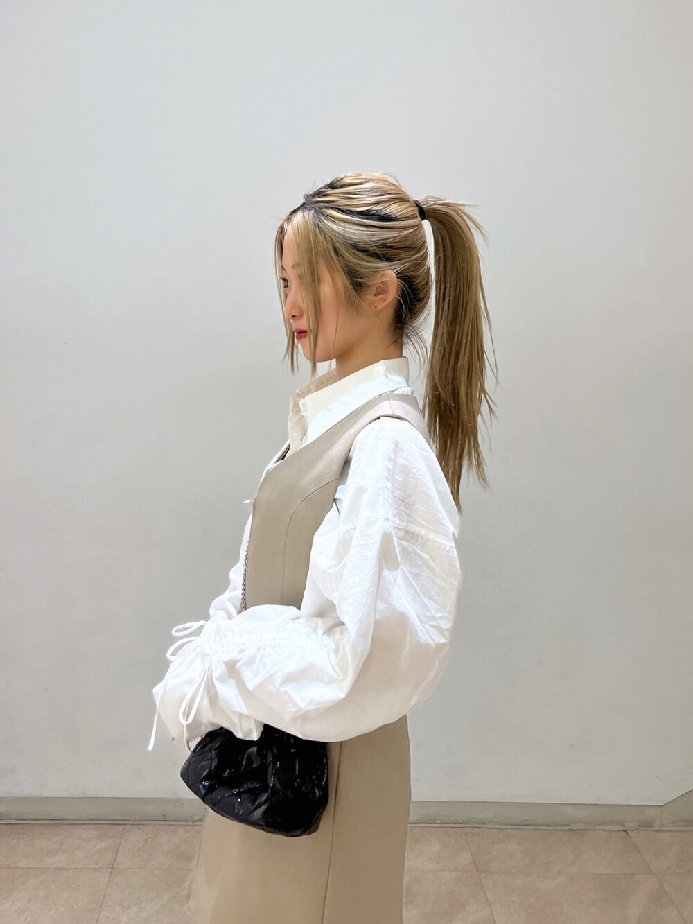 ブラック系のショルダーバッグ、ホワイト系のシャツ/ブラウス、ベージュ系のワンピースを着用したレディースの春コーディネートの5枚目の写真