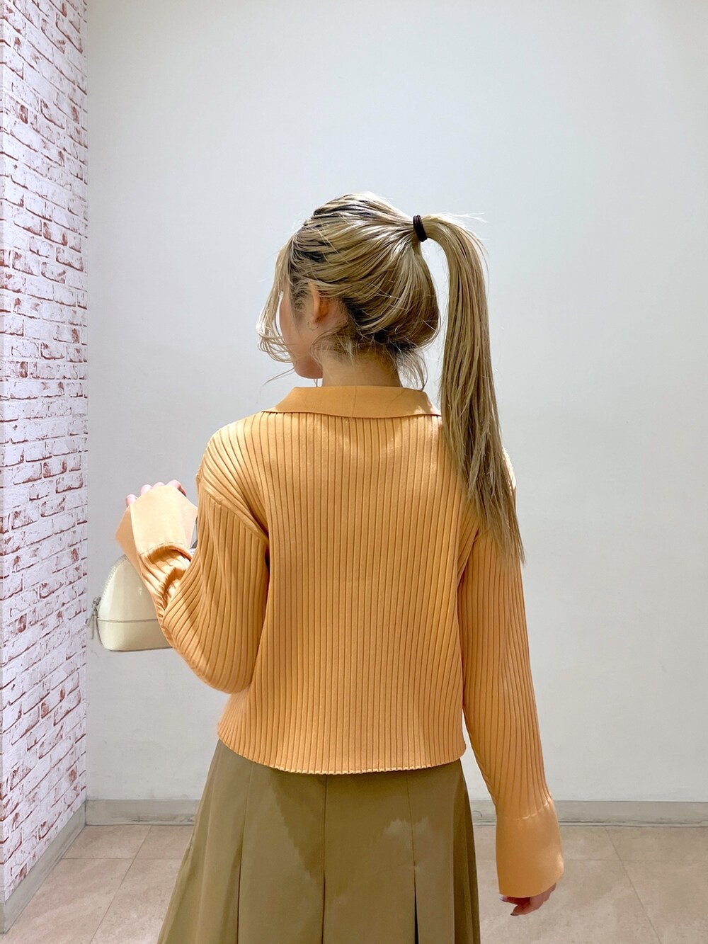 ベージュ系のニット/セーター、ホワイト系のショルダーバッグ、ベージュ系のスカートを着用したレディースの冬コーディネートの8枚目の写真