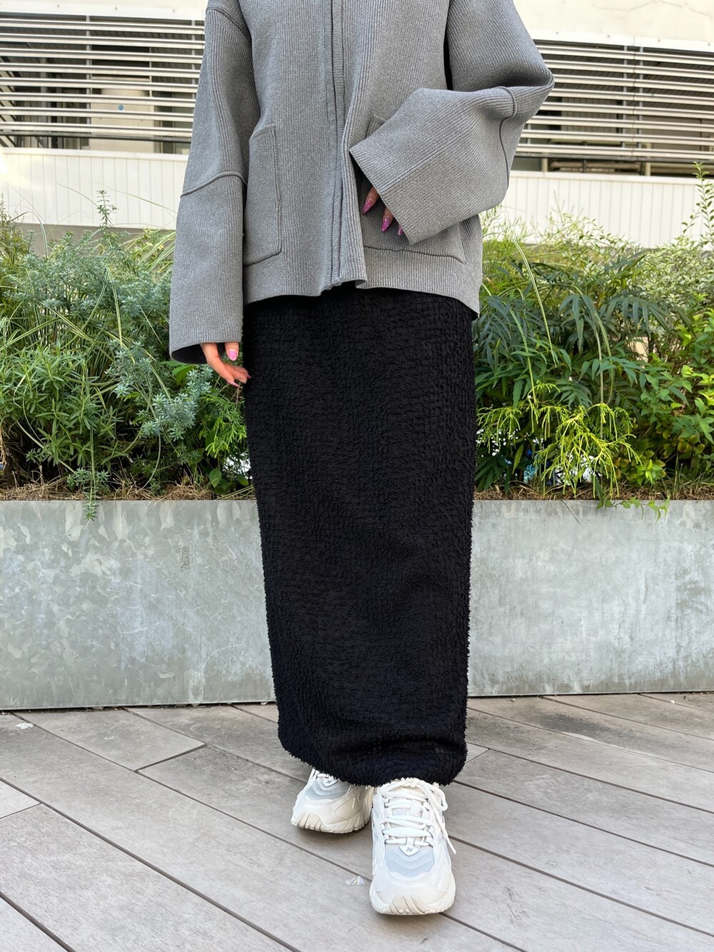 グレー系のカーディガン/ボレロ、ブラック系のスカート、ホワイト系のスニーカーを着用したレディースの秋コーディネートの7枚目の写真