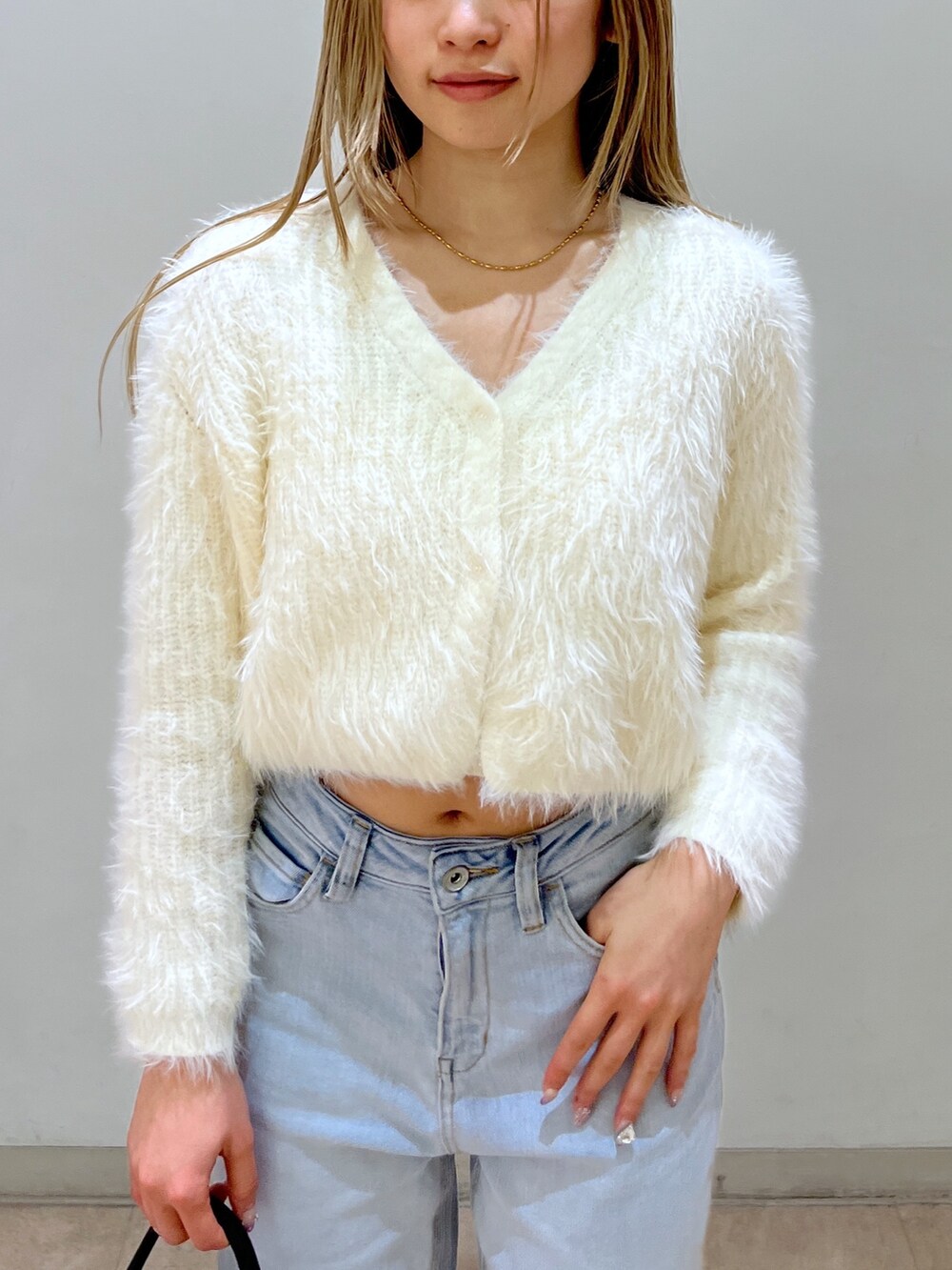 ホワイト系のカーディガン/ボレロ、ブルー系のデニムパンツ、ブラック系のショルダーバッグを着用したレディースの春コーディネートの4枚目の写真