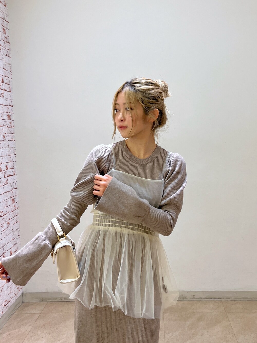 ホワイト系のショルダーバッグ、ブラック系のブーツ、ベージュ系のワンピースを着用したレディースの冬コーディネートの6枚目の写真