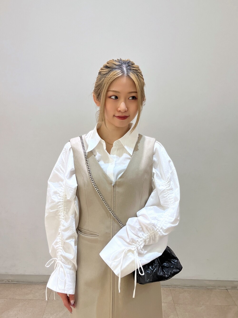 ブラック系のショルダーバッグ、ホワイト系のシャツ/ブラウス、ベージュ系のワンピースを着用したレディースの春コーディネートの4枚目の写真