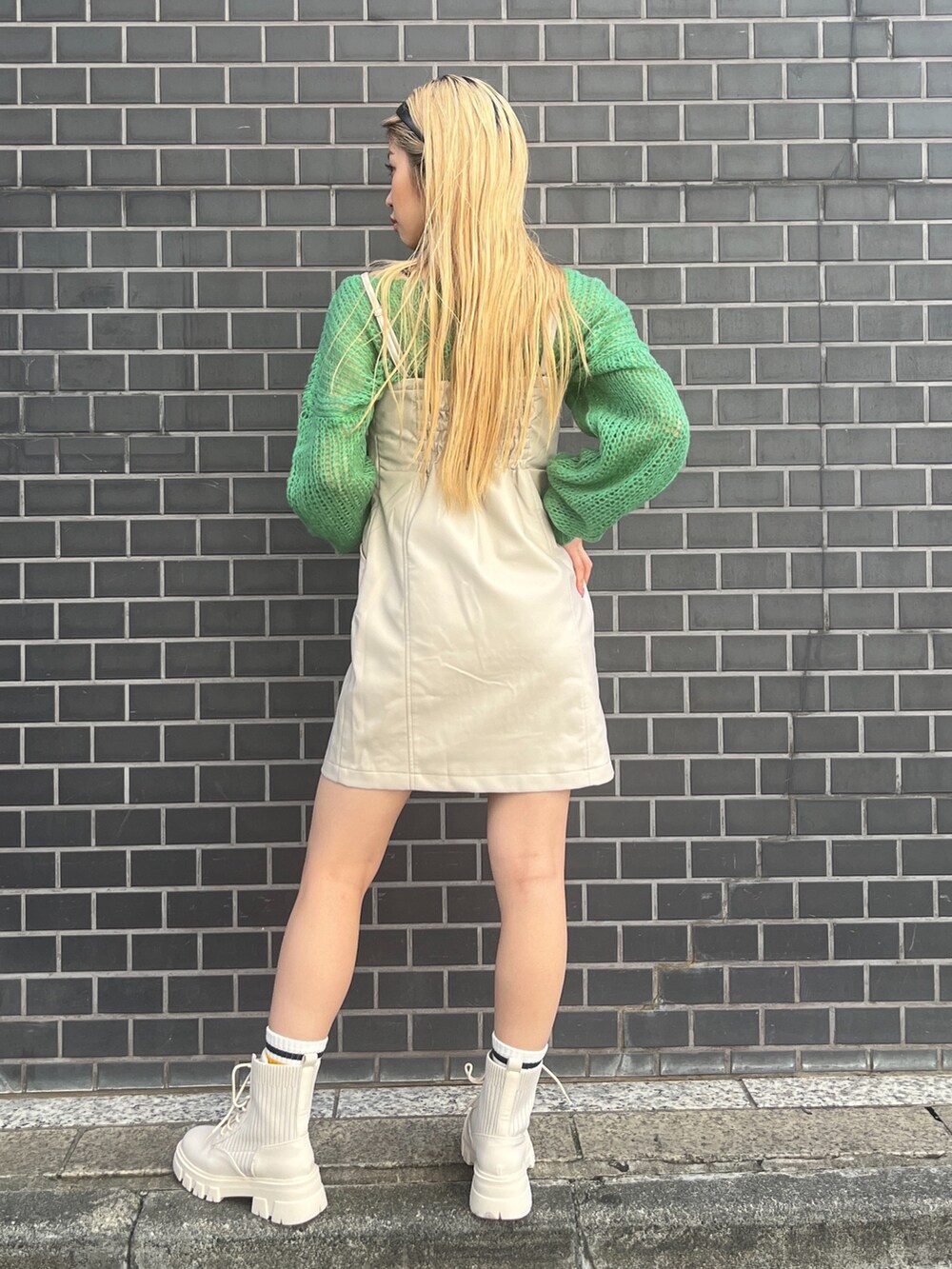 グリーン系のニット/セーター、ホワイト系のワンピース、ホワイト系のブーツを着用したレディースの秋コーディネートの3枚目の写真