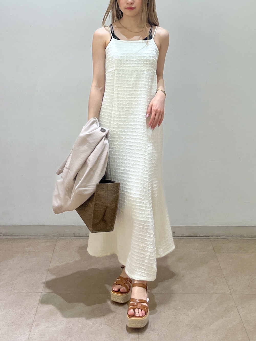 ベージュ系のテーラードジャケット、ブラウン系のショルダーバッグ、ホワイト系のワンピースを着用したレディースの春コーディネートの7枚目の写真