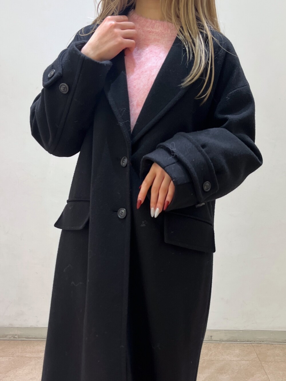 ピンク系のニット/セーター、ブラック系のチェスターコート、ブラック系のブーツを着用したレディースの冬コーディネートの10枚目の写真