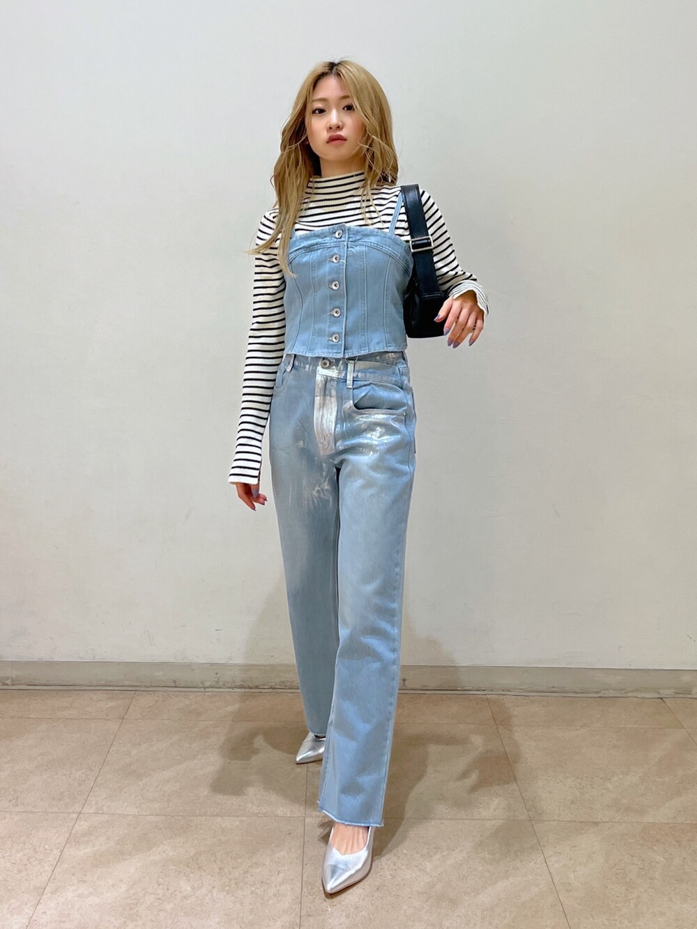 ブルー系のベスト、ホワイト系のニット/セーター、ブラック系のショルダーバッグを着用したレディースの冬コーディネートの3枚目の写真