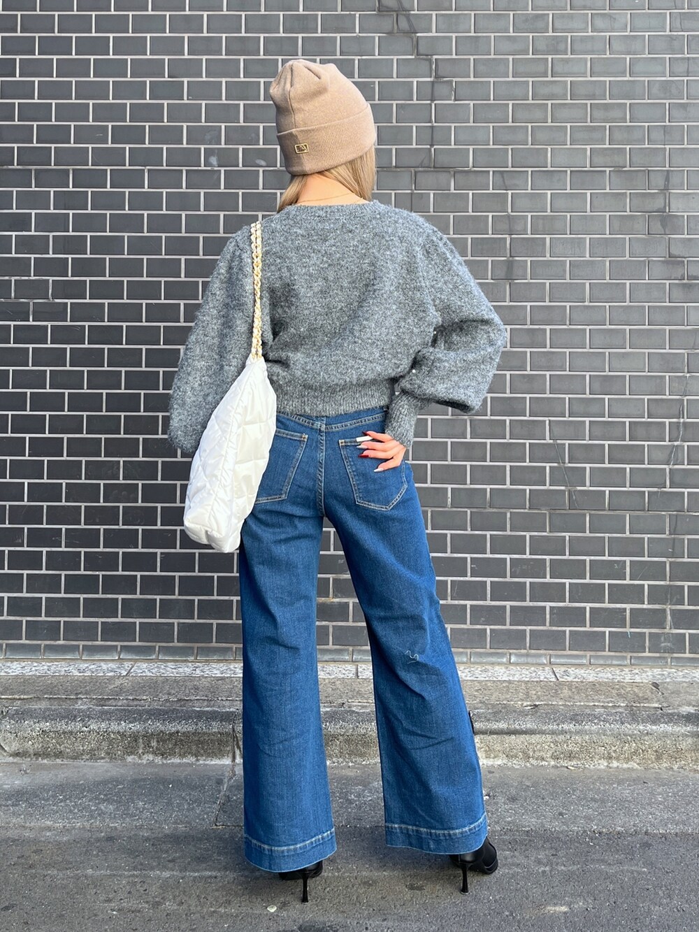 ブルー系のデニムパンツ、グレー系のニット/セーター、ホワイト系のトートバッグを着用したレディースの冬コーディネートの3枚目の写真