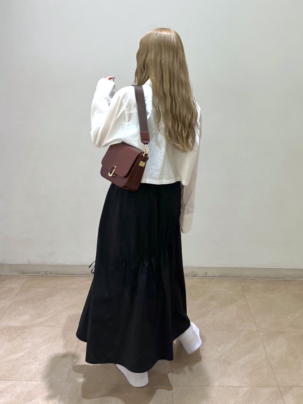 ブラック系のスカート、ホワイト系のシャツ/ブラウス、ブラウン系のショルダーバッグを着用したレディースの春コーディネートの4枚目の写真