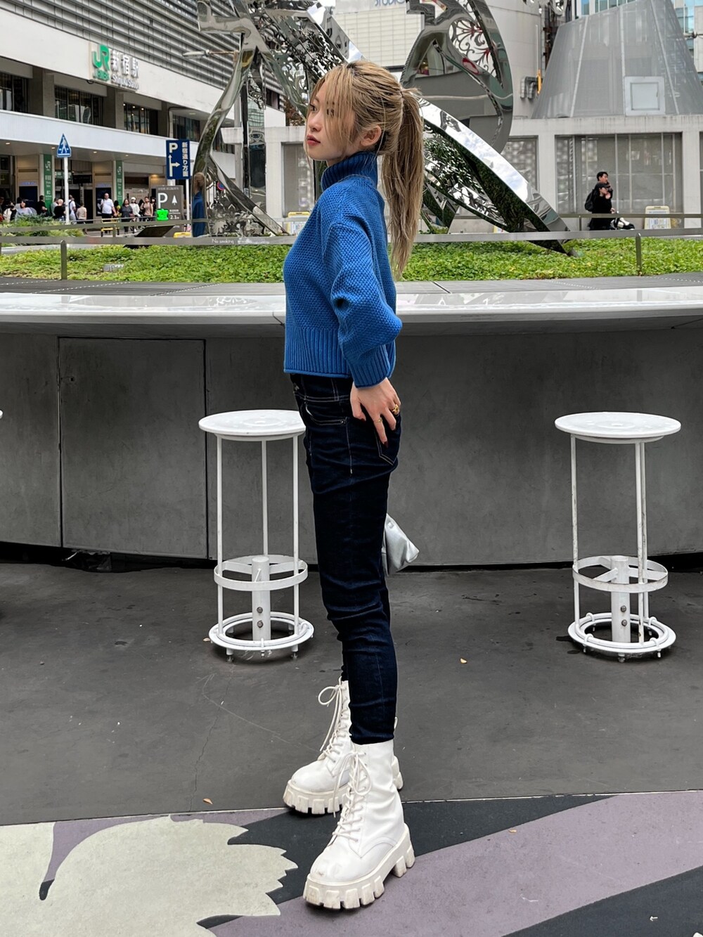 ブルー系のニット/セーター、ブルー系のデニムパンツ、シルバー系のショルダーバッグを着用したレディースの秋コーディネートの3枚目の写真