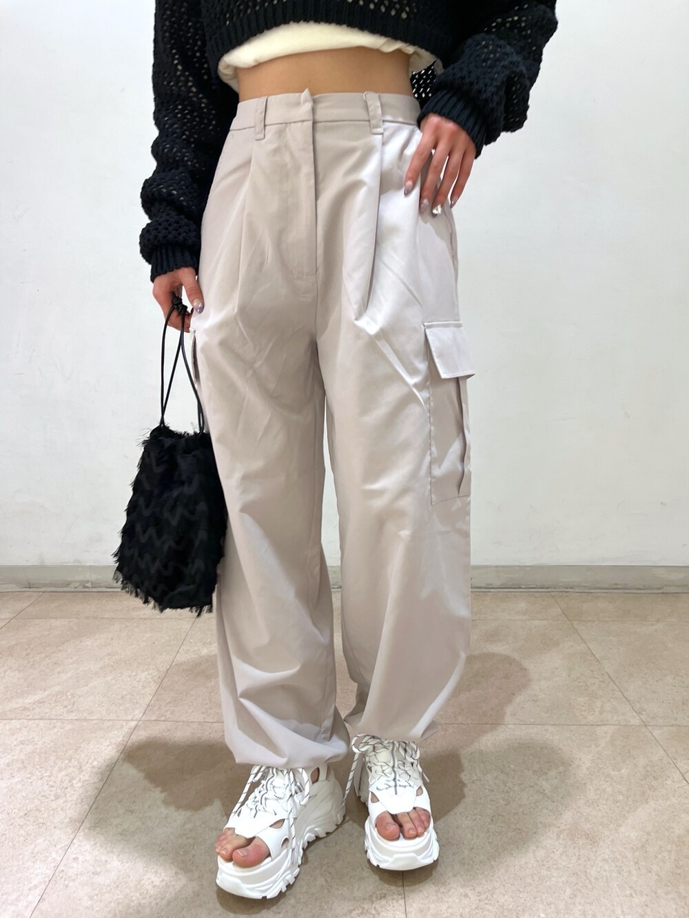 ベージュ系のカーゴパンツ、ブラック系のニット/セーター、ブラック系のハンドバッグを着用したレディースの春コーディネートの9枚目の写真