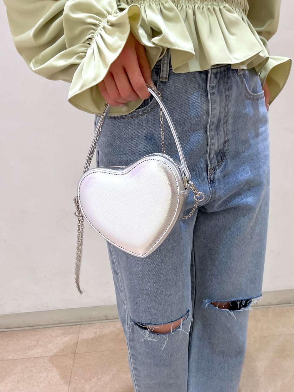 グリーン系のシャツ/ブラウス、シルバー系のショルダーバッグ、ブルー系のデニムパンツを着用したレディースの春コーディネートの10枚目の写真