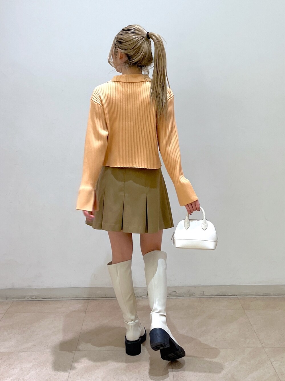 ベージュ系のニット/セーター、ホワイト系のショルダーバッグ、ベージュ系のスカートを着用したレディースの冬コーディネートの5枚目の写真