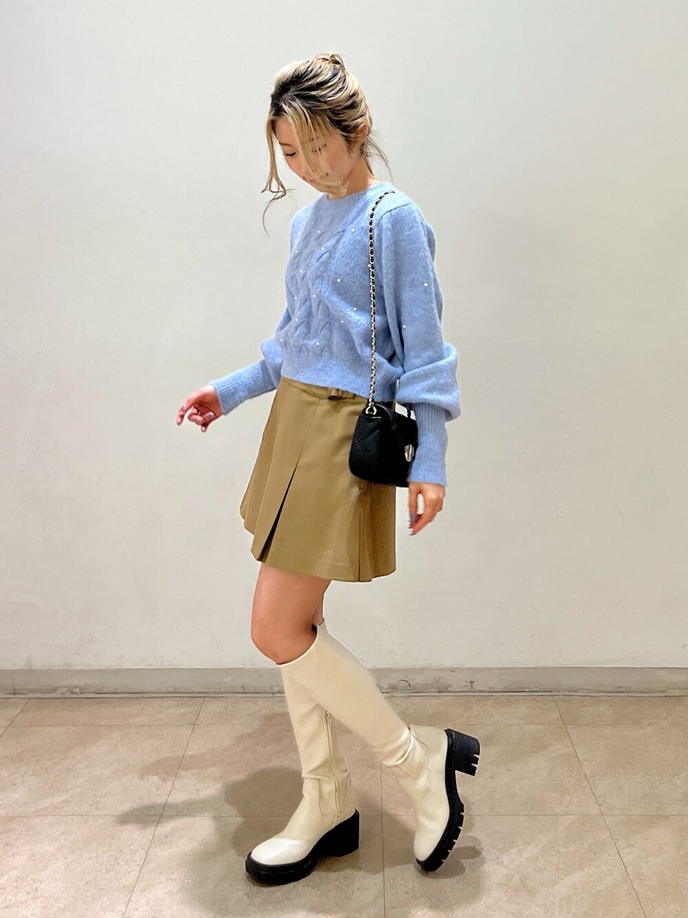 ブルー系のニット/セーター、ブラック系のショルダーバッグ、ベージュ系のスカートを着用したレディースの冬コーディネートの3枚目の写真