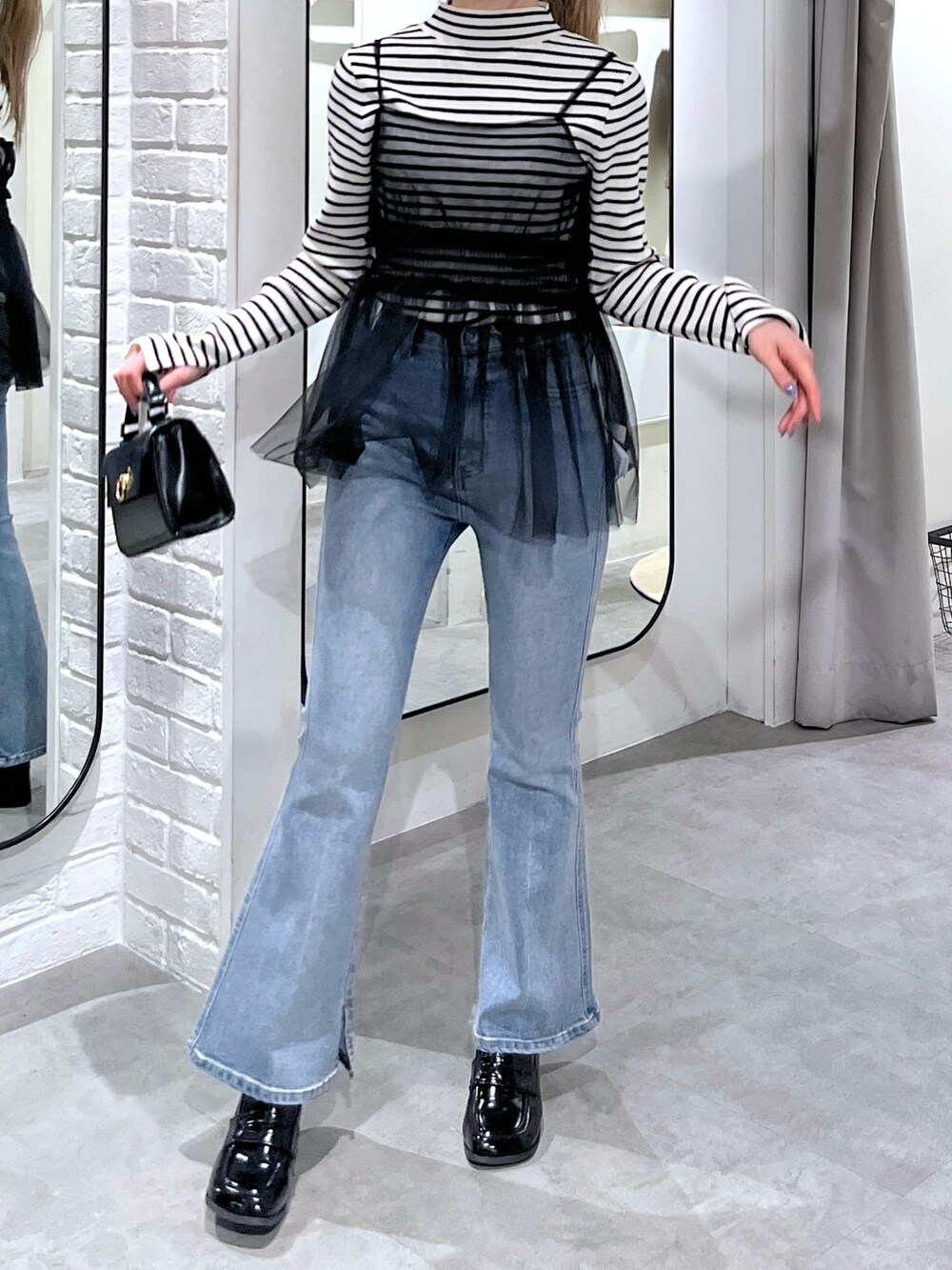 ホワイト系のニット/セーター、ブラック系のシャツ/ブラウス、ブルー系のデニムパンツを着用したレディースの冬コーディネートの5枚目の写真