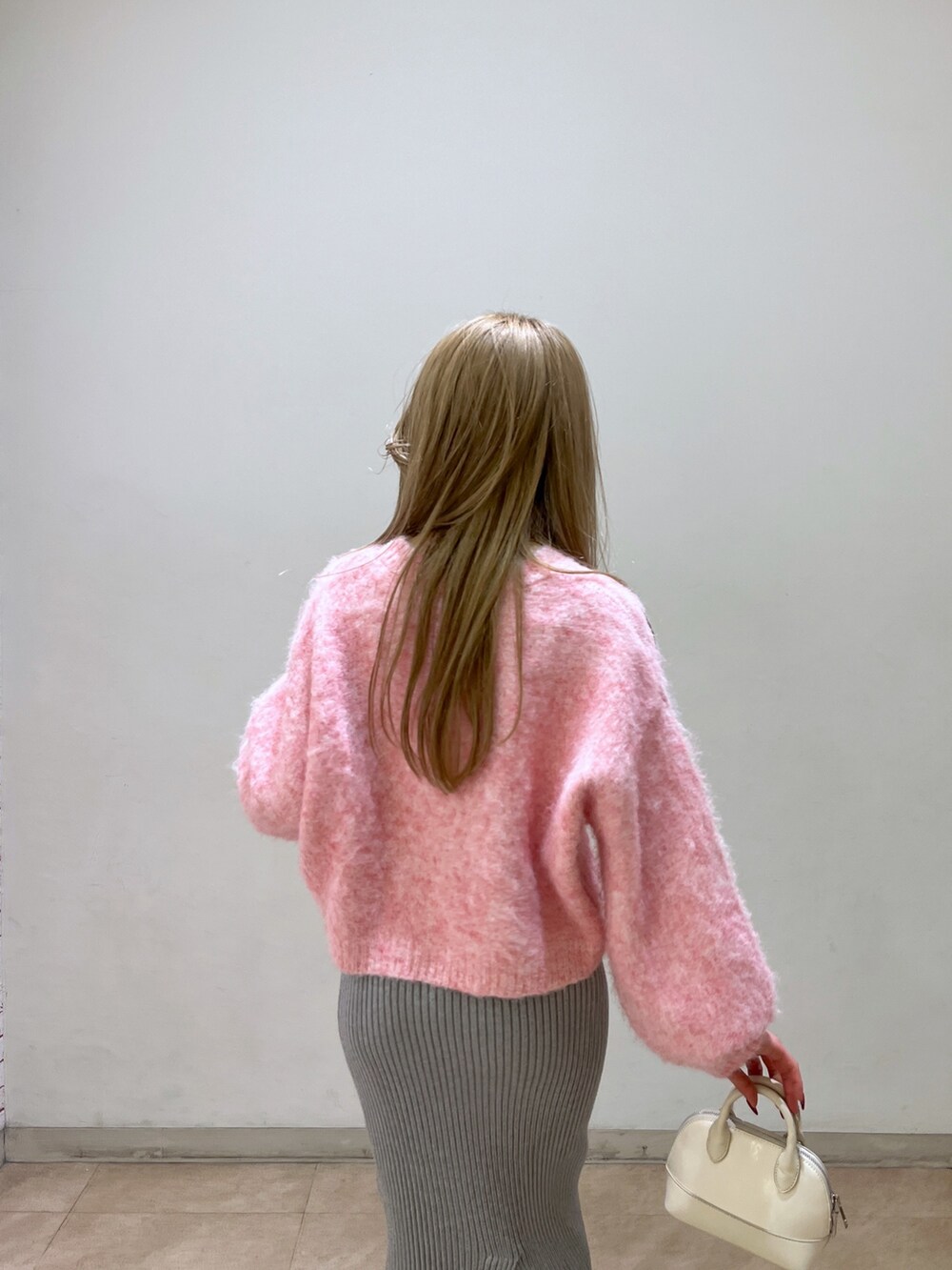 ピンク系のニット/セーター、ブラック系のブーツ、ホワイト系のショルダーバッグを着用したレディースの冬コーディネートの8枚目の写真