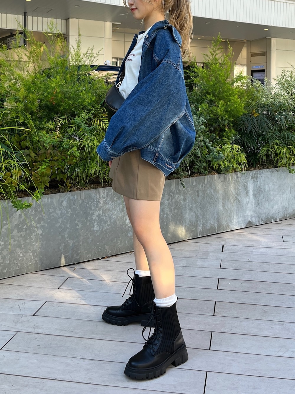 ブルー系のデニムジャケット、ホワイト系のTシャツ/カットソー、ブラック系のボディバッグ/ウエストポーチを着用したレディースの秋コーディネートの4枚目の写真