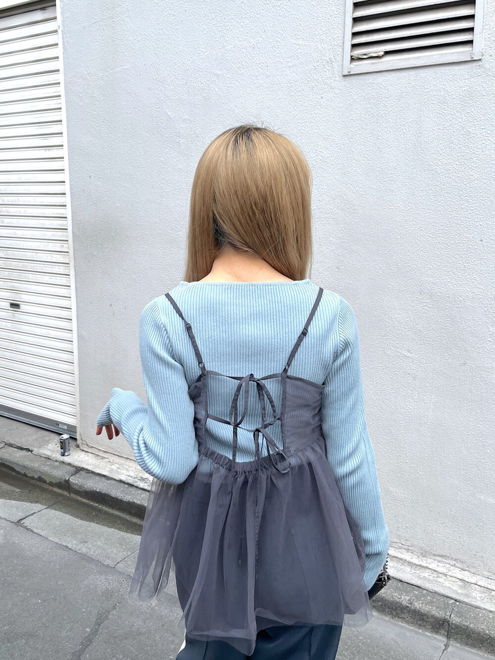 ブルー系のニット/セーター、ブラック系のショルダーバッグ、グレー系のシャツ/ブラウスを着用したレディースの冬コーディネートの5枚目の写真