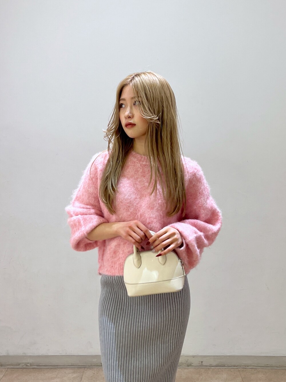 ピンク系のニット/セーター、ブラック系のブーツ、ホワイト系のショルダーバッグを着用したレディースの冬コーディネートの7枚目の写真