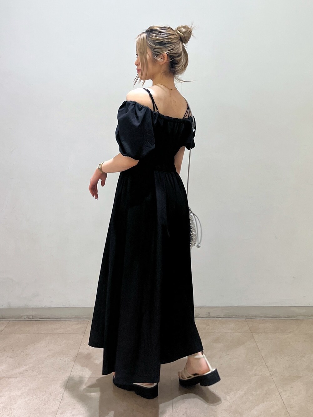 ブラック系のワンピース、シルバー系のハンドバッグ、ホワイト系のサンダルを着用したレディースの春コーディネートの3枚目の写真