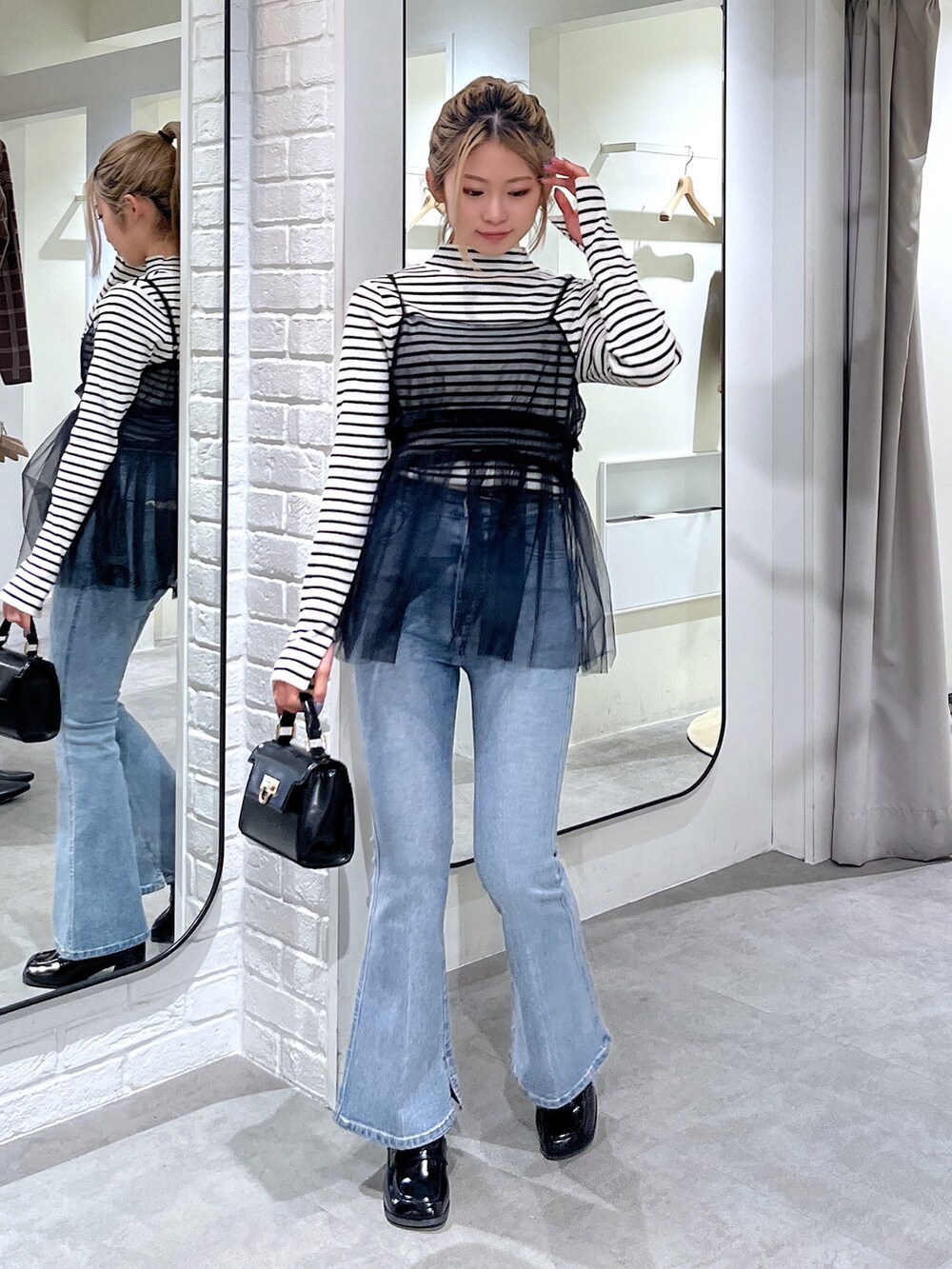 ホワイト系のニット/セーター、ブラック系のシャツ/ブラウス、ブルー系のデニムパンツを着用したレディースの冬コーディネートの2枚目の写真