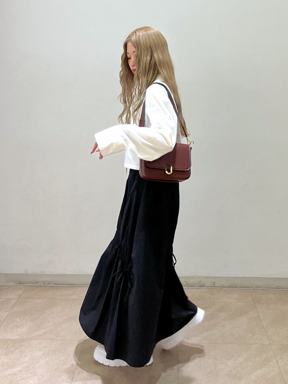 ブラック系のスカート、ホワイト系のシャツ/ブラウス、ブラウン系のショルダーバッグを着用したレディースの春コーディネートの3枚目の写真