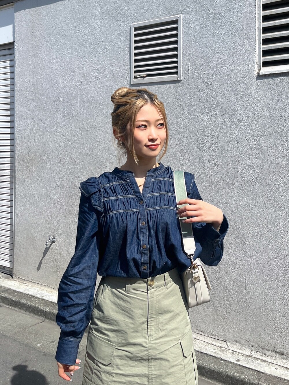 グリーン系のスカート、ホワイト系のショルダーバッグ、ブルー系のシャツ/ブラウスを着用したレディースの春コーディネートの6枚目の写真