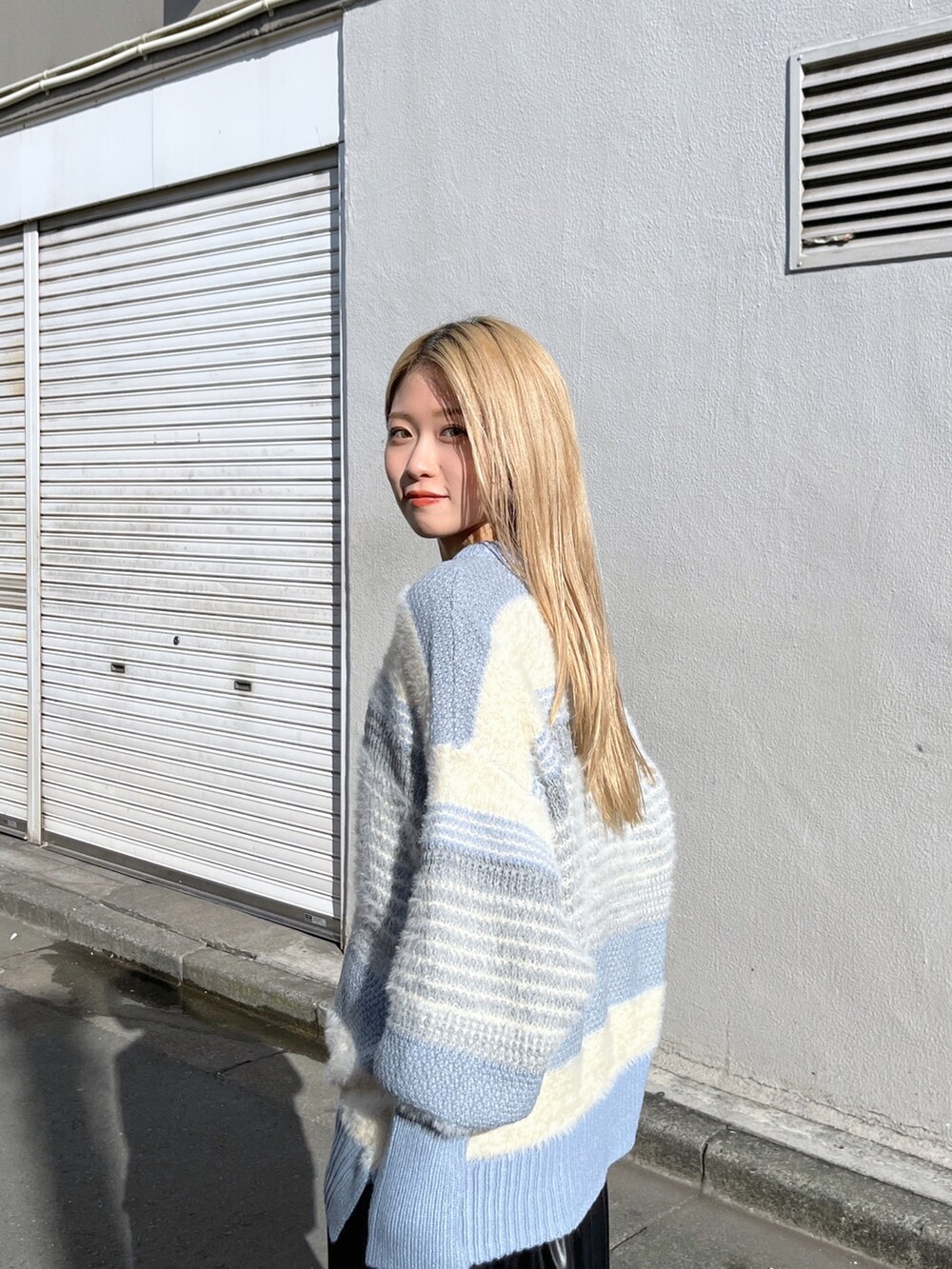 ブルー系のニット/セーター、ブラック系のスカート、ブラック系のブーツを着用したレディースの冬コーディネートの6枚目の写真