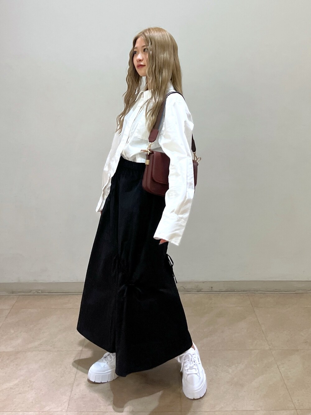 ブラック系のスカート、ホワイト系のシャツ/ブラウス、ブラウン系のショルダーバッグを着用したレディースの春コーディネートの2枚目の写真